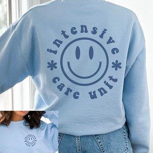 May include: Light blue sweatshirt with a blue smiley face and the text "intensive care unit" in a retro font.
