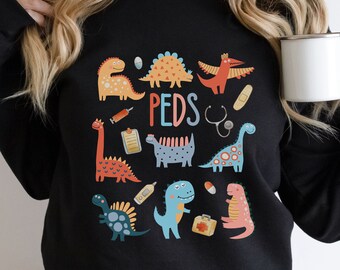 May include: Black sweatshirt with a graphic print of colorful dinosaurs and medical symbols. The text "PEDS" is printed in the center of the design.