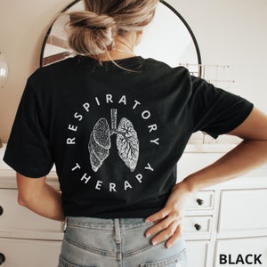 Pode incluir: Camiseta preta com um gr&aacute;fico branco de pulm&otilde;es e as palavras "RESPIRATORY THERAPY" em um design circular. A camiseta tem gola redonda. A palavra "BLACK" est&aacute; impressa no canto inferior direito.