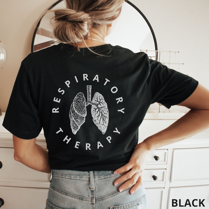 Pode incluir: Camiseta preta com um gr&aacute;fico branco de pulm&otilde;es e as palavras "RESPIRATORY THERAPY" em um design circular. A camiseta tem gola redonda. A palavra "BLACK" est&aacute; impressa no canto inferior direito.