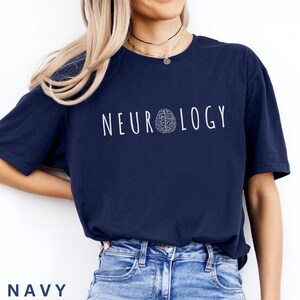 K&ouml;nnte beinhalten: Marineblaues T-Shirt mit dem Wort "NEUROLOGY" in Wei&szlig; und einer Gehirngrafik. Das Wort "NAVY" ist am unteren Bildrand aufgedruckt. Das Shirt besteht aus einem weichen Material.