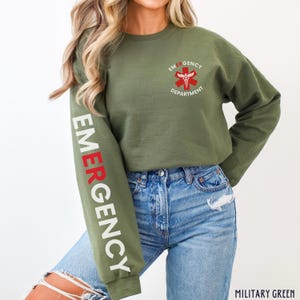 May include: A green sweatshirt with the text "EMERGENCY DEPARTMENT" and a red medical symbol on the front. The left sleeve has the word "EMERGENCY" written vertically in white and red letters.