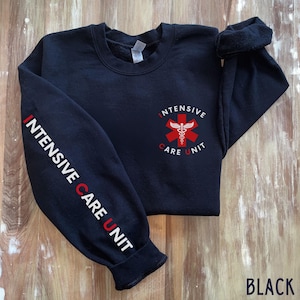 May include: Black sweatshirt with the words "INTENSIVE CARE UNIT" printed in white and red on the left sleeve. The front of the sweatshirt features a red and white medical symbol with the words "INTENSIVE CARE UNIT".