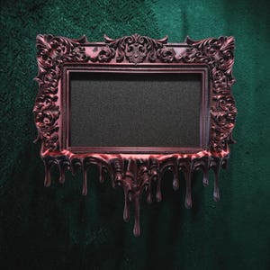 May include: A rectangular picture frame with a dark metallic red finish and ornate, intricate scrollwork detailing. The bottom edge of the frame features a distinct dripping or melting effect, with elongated, smooth resin-like drips extending downward.