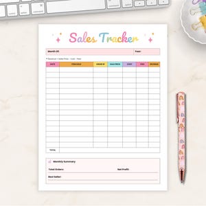 Puede incluir: Una hoja de seguimiento de ventas blanca con el texto "Sales Tracker" en letras coloridas. Un bolígrafo con un patrón de arcoíris y un plato pequeño con clips de papel coloridos están a la derecha. Un teclado está en la esquina superior izquierda.