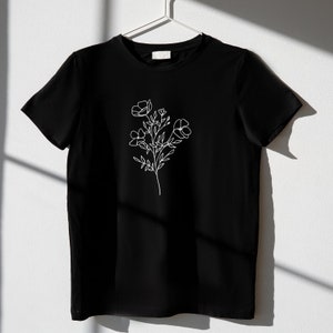 May include: A black t-shirt with a white line drawing of a flower on the front.