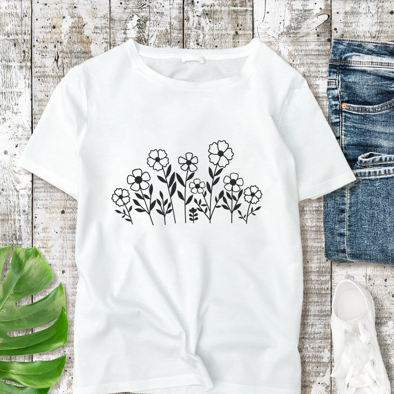 May include: White t-shirt with a black floral design. The design features a row of stylized flowers with stems and leaves.