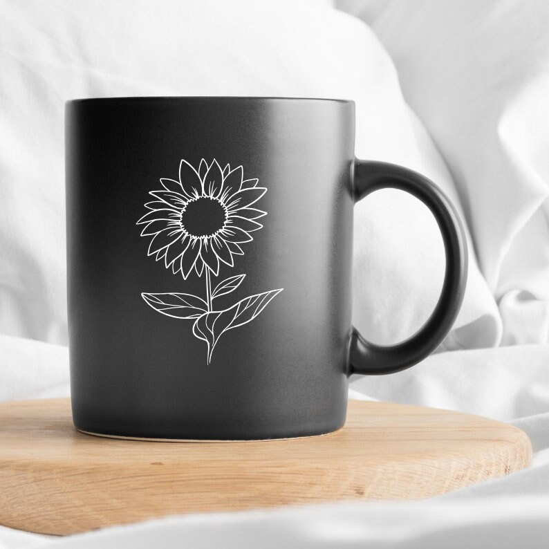 May include: Black ceramic mug with a white outline of a sunflower.