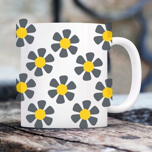 May include: White ceramic mug with a pattern of gray flowers with yellow centers.