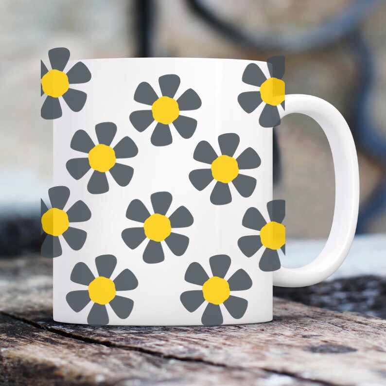 May include: White ceramic mug with a pattern of gray flowers with yellow centers.