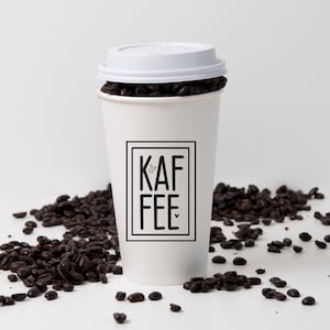 May include: White to-go coffee cup with a black and white logo that says "KAF FEE" with a small heart above the "E". The cup is filled with coffee beans and has a white lid.