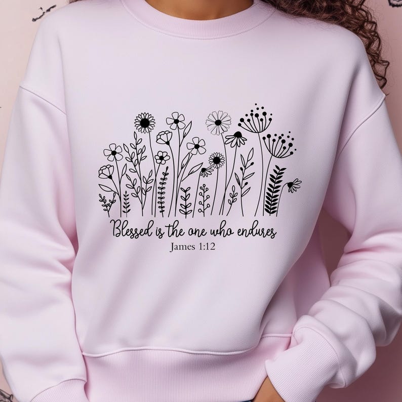 May include: Pink sweatshirt with a black floral design and the text "Blessed is the one who endures, James 1:12".