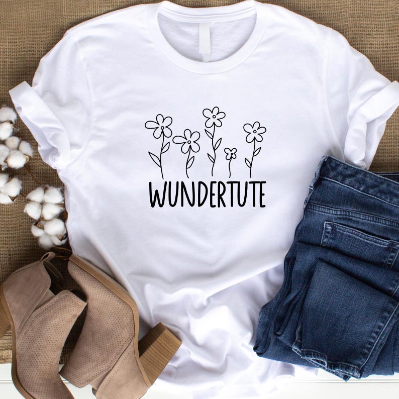 Op de afbeelding: Wit T-shirt met een zwarte afbeelding van gestileerde bloemen en de tekst "WUNDERtute".