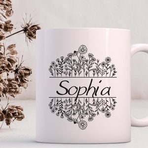 Op de afbeelding: Witte keramische mok met een zwart bloemenontwerp en de naam "Sophia" erop gedrukt.