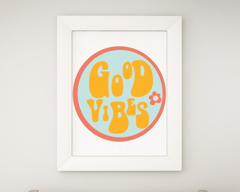 Puede incluir: Un estampado enmarcado con las palabras "GOOD VIBES" en naranja, con letras de estilo retro. El texto est&aacute; dentro de un c&iacute;rculo azul claro con un borde coral y un peque&ntilde;o gr&aacute;fico de flores. El marco es blanco.