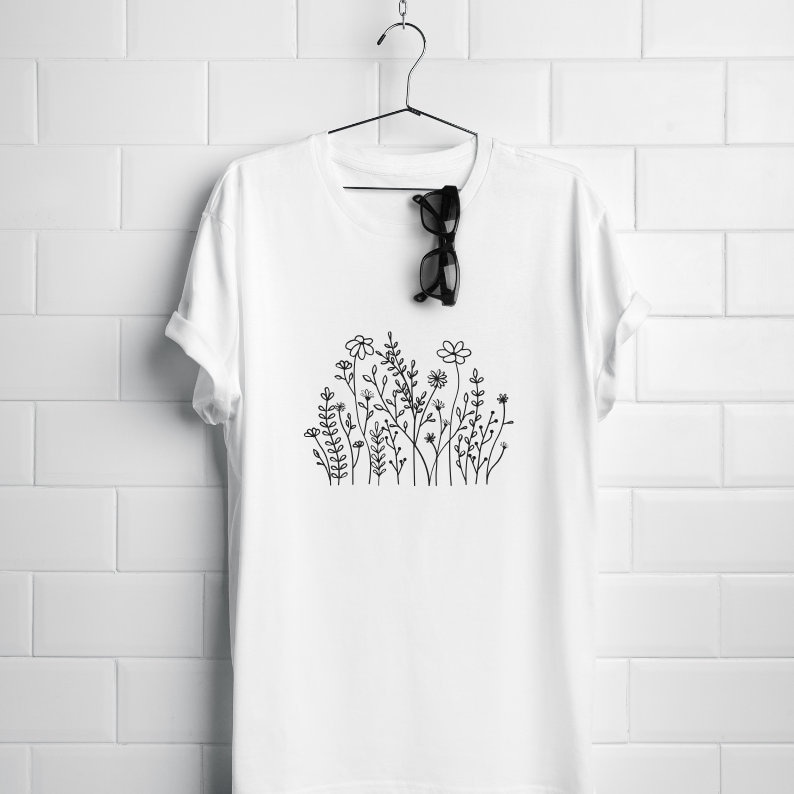 May include: White t-shirt with a black line drawing of a cluster of flowers and leaves.