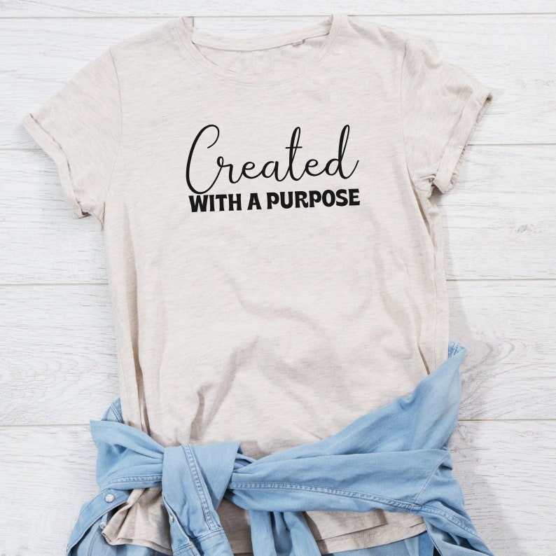 May include: A beige t-shirt with the text "Created with a purpose" in black lettering.