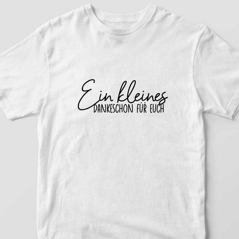 K&ouml;nnte beinhalten: Wei&szlig;es T-Shirt mit schwarzem Text, der "Ein kleines Dankesch&ouml;n f&uuml;r euch" lautet.