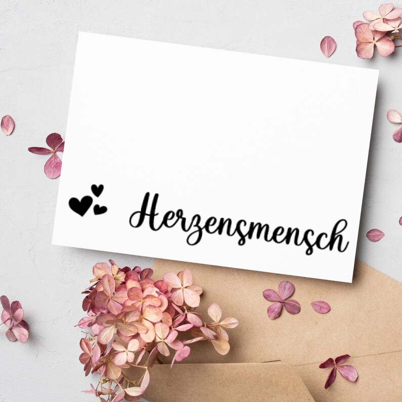 May include: A white card with black text that reads "Herzensmensch" and three small black hearts.