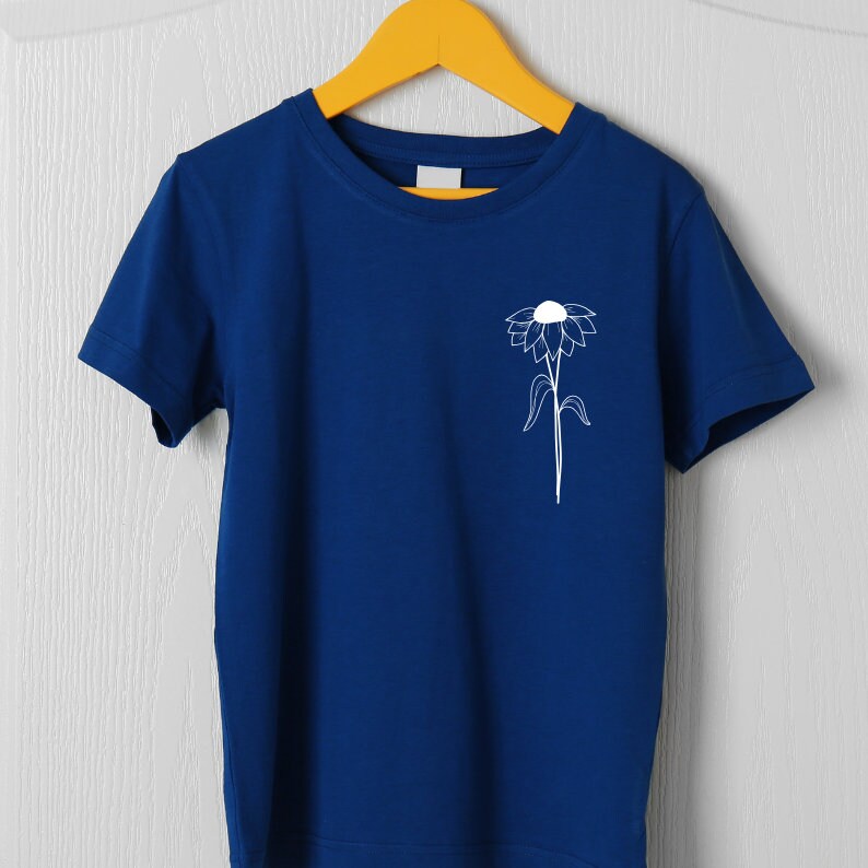 May include: A royal blue t-shirt with a white outline of a flower on the left chest.