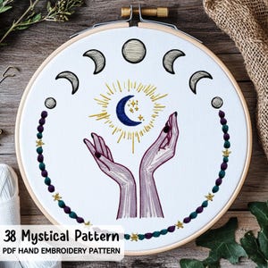 May include: An embroidery hoop featuring a mystical design. The design includes a crescent moon, sun, and hands reaching upwards. The border is decorated with beads and stars. The text "38 Mystical Pattern" and "PDF Hand Embroidery Pattern" is visible.
