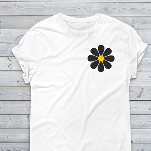 May include: White t-shirt with a black daisy with a yellow center.