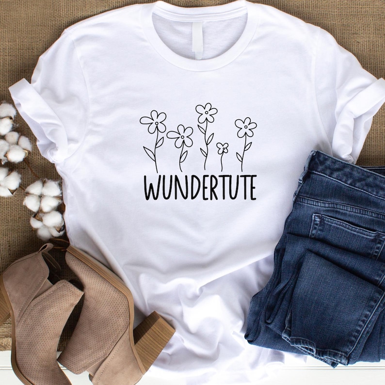 K&ouml;nnte beinhalten: Wei&szlig;es T-Shirt mit einer schwarzen Grafik von stilisierten Blumen und dem Text "WUNDERTUTE".