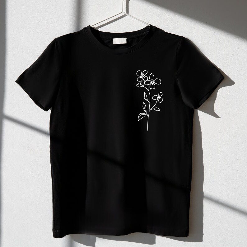 May include: A black t-shirt with a white line drawing of a flower on the left side of the chest.