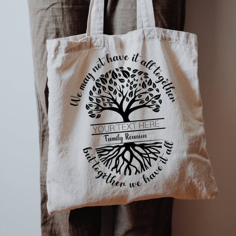 May include: A white canvas tote bag with a black tree design and the text "We may not have it all together but together we have it all". The text is in a cursive font. There is a blank space for text that says "YOUR TEXT HERE" and "Family Reunion".