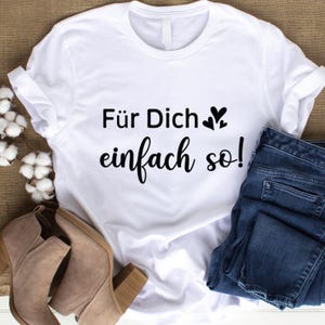 May include: White t-shirt with the German text "F&uuml;r Dich einfach so!" in black script. The shirt is paired with blue jeans and tan ankle boots. The text includes two small heart symbols.