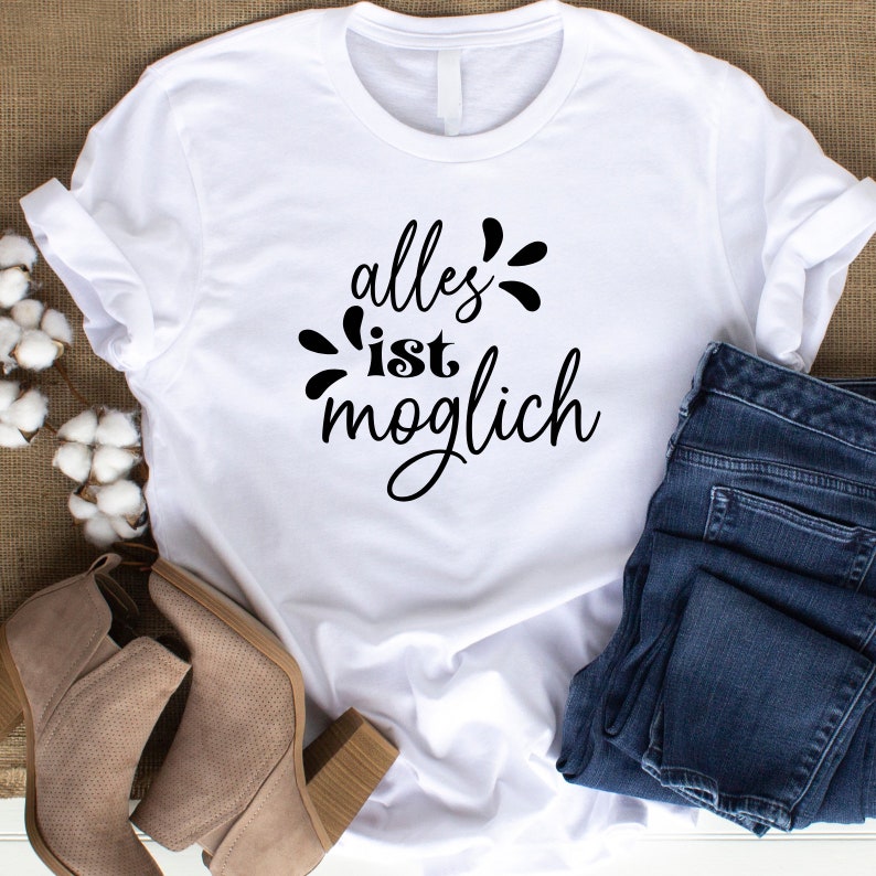 Peut inclure: T-shirt blanc avec un texte noir qui dit "alles ist moglich", ce qui se traduit par "tout est possible".