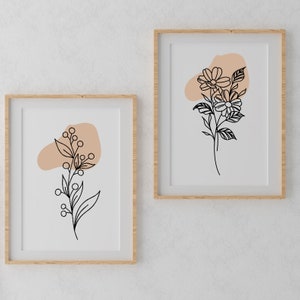 May include: Two framed prints featuring minimalist line drawings of flowers and foliage on a white background. Both prints include a peach-coloured abstract shape.