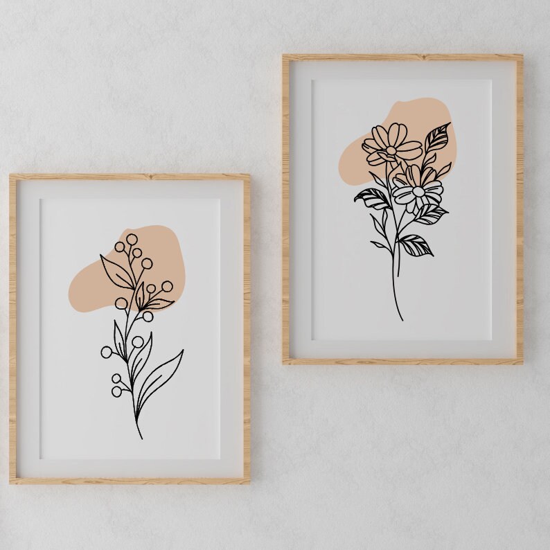 May include: Two framed prints featuring minimalist line drawings of flowers and foliage on a white background. Both prints include a peach-coloured abstract shape.