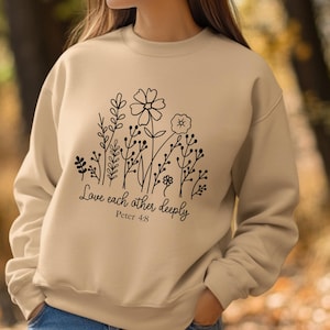 May include: A beige sweatshirt with a black floral design and the text "Love each other deeply Peter 4:8".