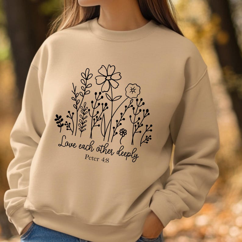 May include: A beige sweatshirt with a black floral design and the text "Love each other deeply Peter 4:8".