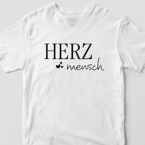 May include: White t-shirt with black text that reads "HERZ mensch" with two small hearts.