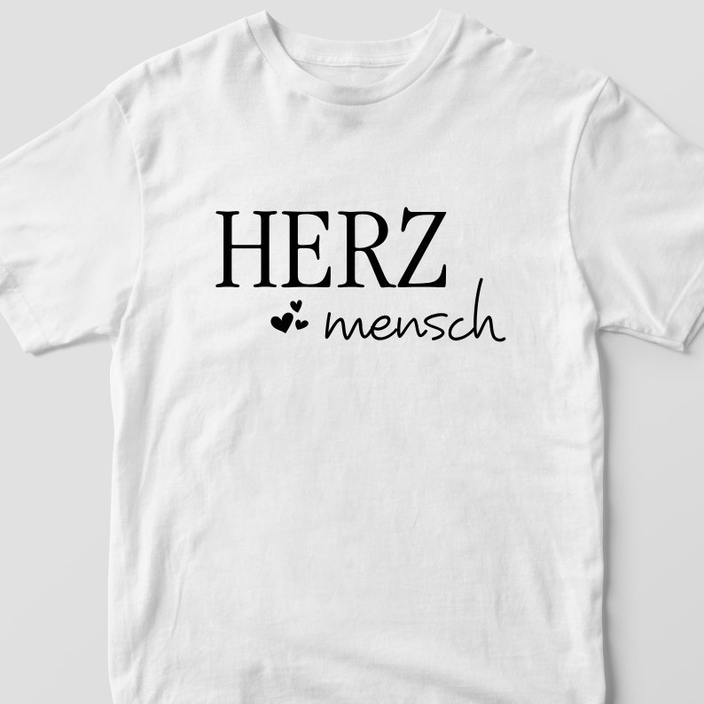May include: White t-shirt with black text that reads "HERZ mensch" with two small hearts.