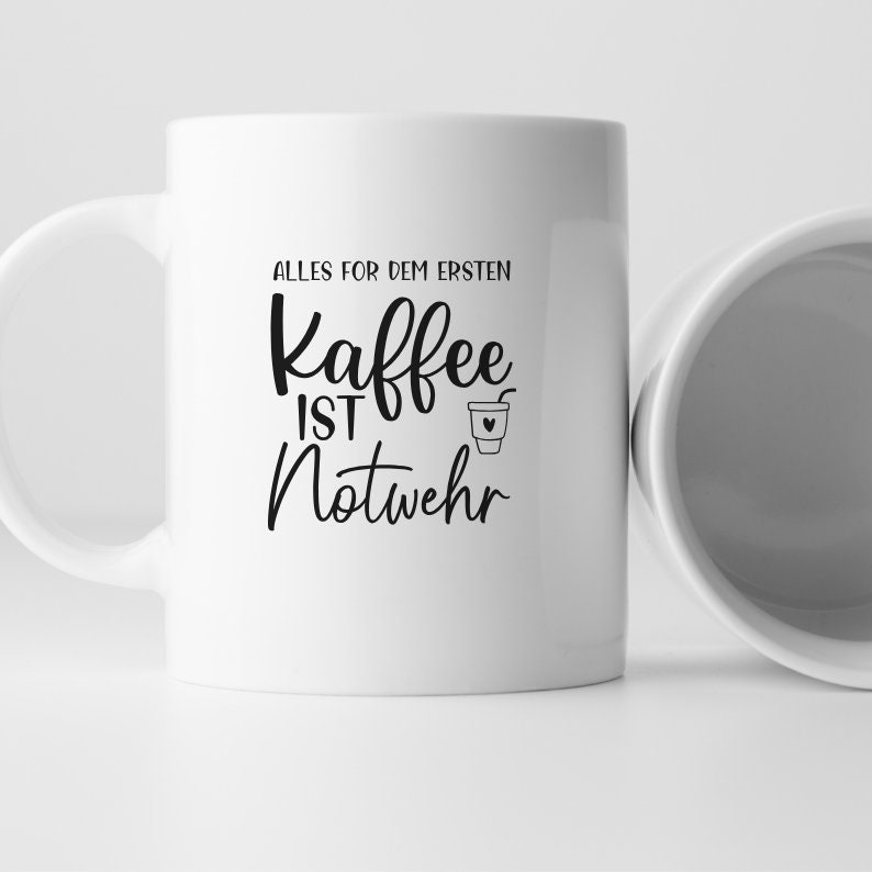 May include: White ceramic coffee mug with black text that reads "Alles for dem ersten Kaffee ist Notwehr" with a small coffee cup icon.