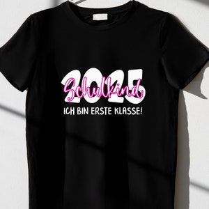 Pode incluir: Camiseta preta com texto branco que diz "2025 Schulkind Ich bin erste Klasse!"