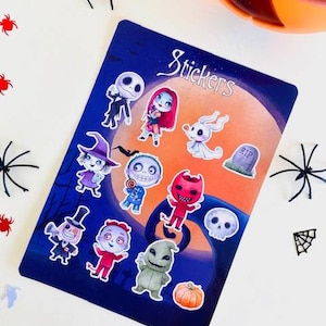 Puede incluir: Una hoja de pegatinas con personajes de Pesadilla Antes de Navidad. Las pegatinas están sobre un fondo azul con una luna y estrellas. El texto "Stickers" está en la parte superior de la hoja.
