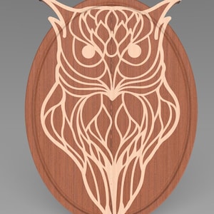 Pode incluir: Uma placa oval de madeira com um design detalhado de uma coruja recortada em branco. Os olhos da coruja são grandes e redondos, e suas penas têm um padrão intrincado.
