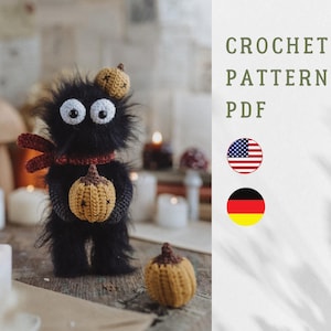 Op de afbeelding: Een zwart gehaakt wezen met grote witte ogen, met een kleine pompoen. Het draagt een rode sjaal en een pompoenhoed. De afbeelding bevat de tekst "CROCHET PATTERN PDF" en de Amerikaanse vlag.