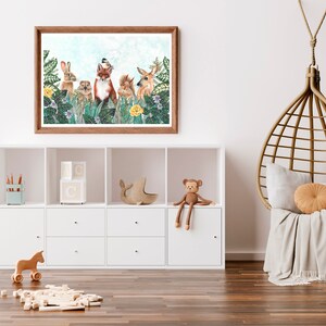 May include: A framed print of a whimsical woodland scene featuring a fox, rabbit, squirrel, deer, and a bird. The animals are surrounded by lush greenery and flowers. The print is in a light wood frame and is hanging on a white wall.