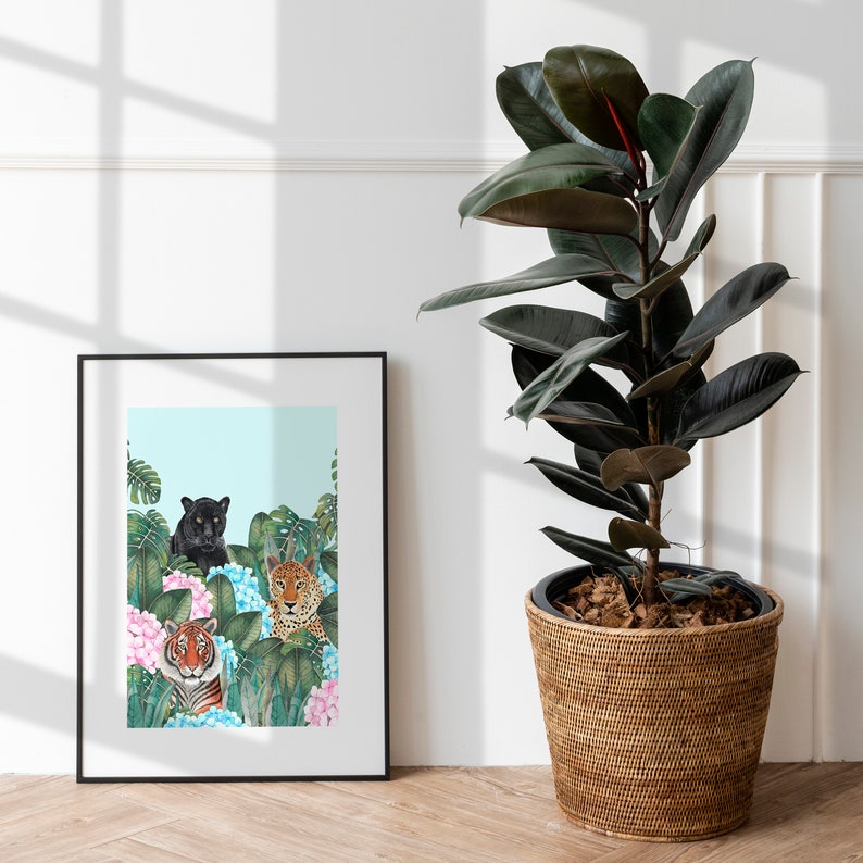 May include: A framed print of a black panther, a tiger, and a leopard in a jungle setting with blue and pink flowers. The print is in a black frame and is hanging on a white wall.