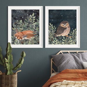 May include: Two framed illustrations, one depicting a sleeping fox in a forest setting with a starry night sky, and the other depicting a sleeping owl in a similar forest setting with a starry night sky.