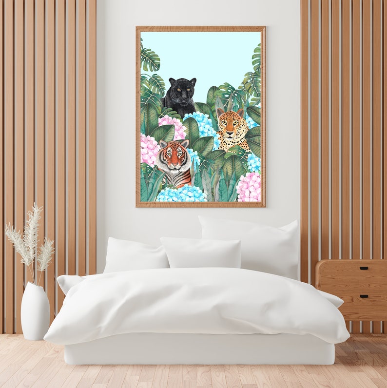 May include: A framed watercolor painting of three wild cats, a black panther, a tiger, and a leopard, peeking out from behind lush green tropical leaves and pink and blue hydrangeas.