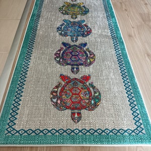 May include: A teal and white runner rug with a border of teal diamonds. The rug features five colorful, patterned turtles in a row.