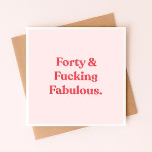 Op de afbeelding: Een vierkante wenskaart met een lichtroze achtergrond en de tekst Forty & Fucking Fabulous in dikgedrukte rode letters. De kaart ligt op een effen bruine envelop, wat zorgt voor een eenvoudige en directe visuele presentatie.