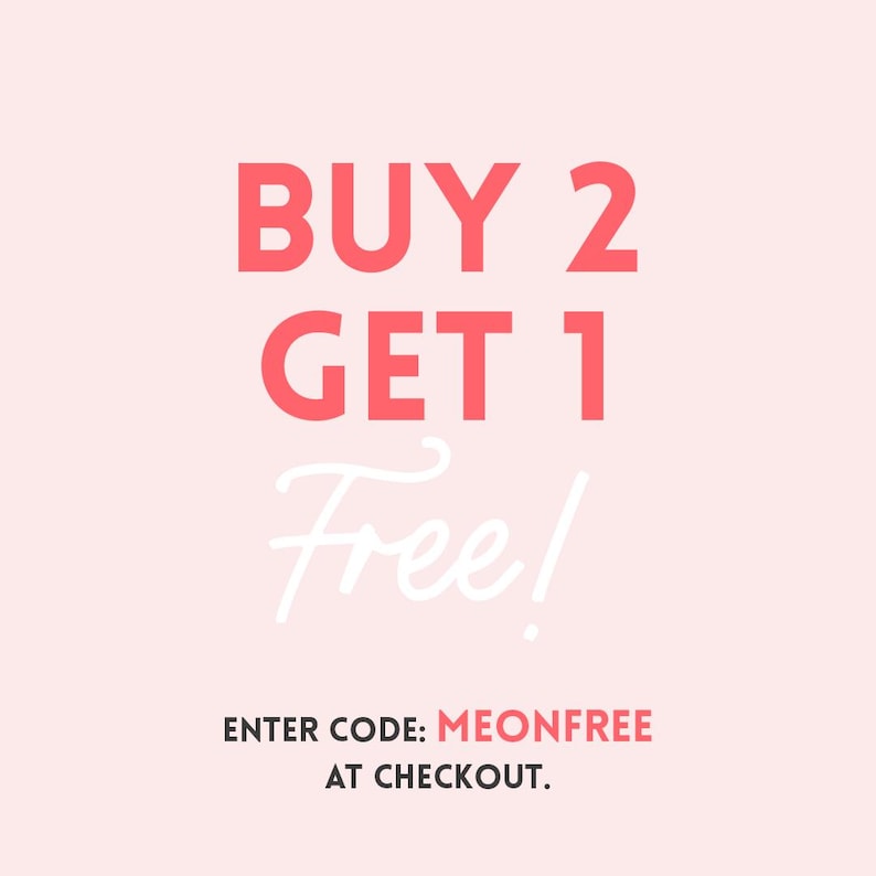 May include: A light pink background with the text "BUY 2 GET 1 Free!" in coral-colored block letters and white cursive. Below, the text "ENTER CODE: MEONFREE AT CHECKOUT." is displayed in a smaller font.
