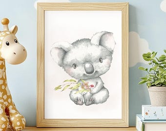 May include: A framed wall art print featuring a watercolor illustration of a fluffy gray koala holding a small green eucalyptus branch. The koala has large ears, a dark nose, and soft fur, presented in a light-colored wooden frame on a shelf.